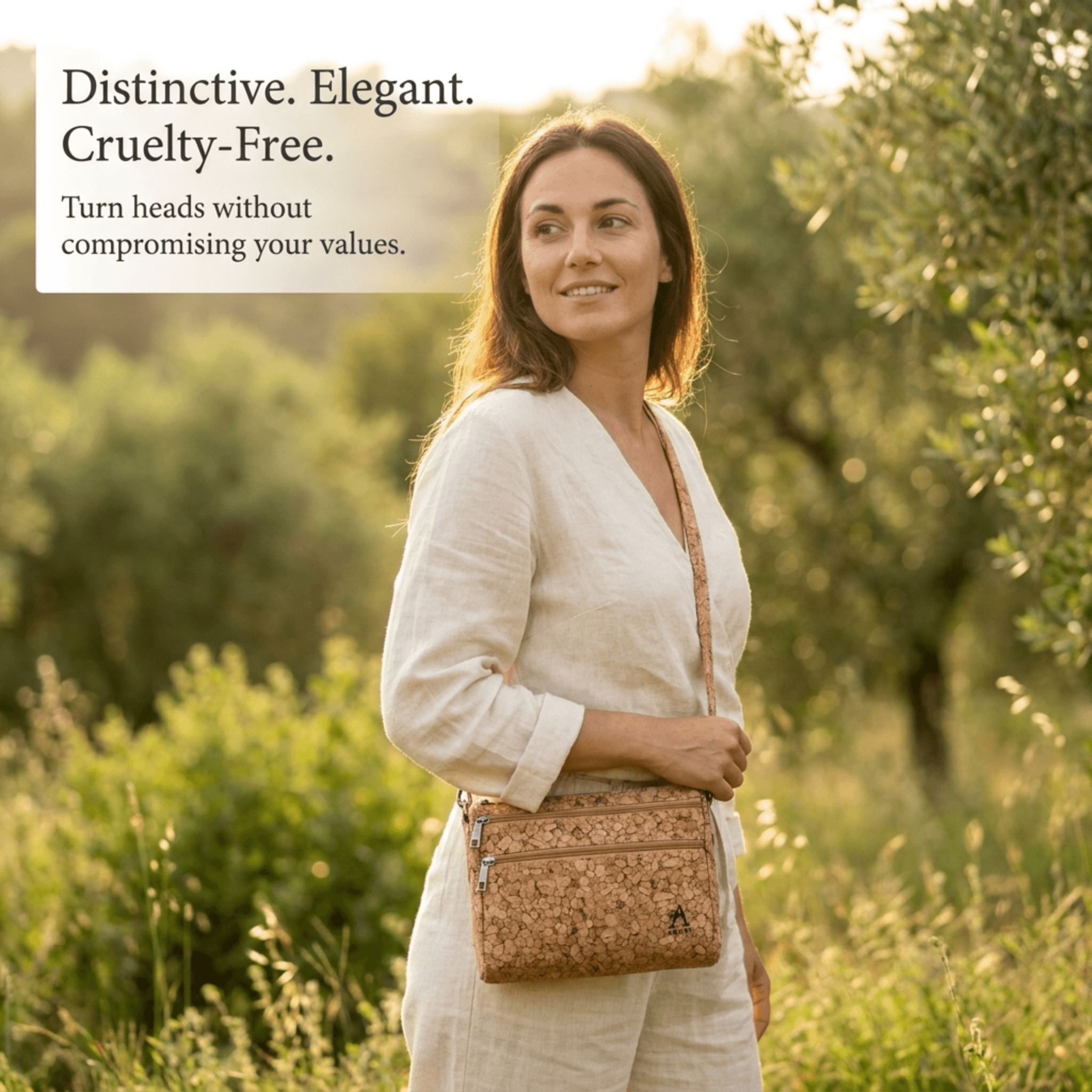 Woman standing in a sunlit field with tall grasses, wearing a light beige outfit and a patterned tan crossbody bag.