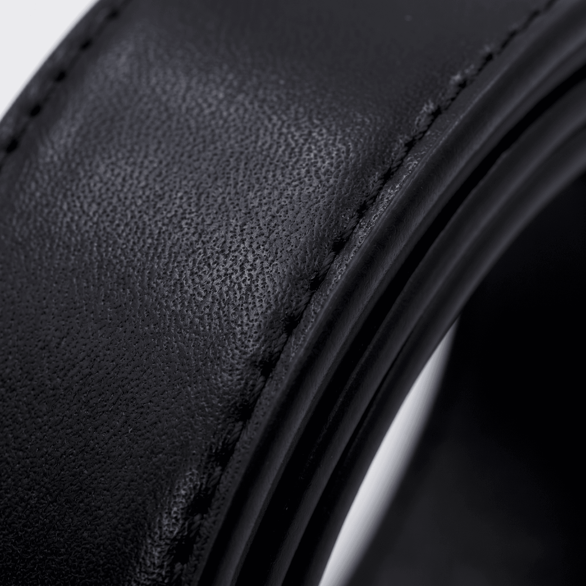 Close-up of black textured leather with a stitched seam along the edge